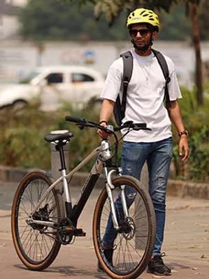 A rider walking an EMotorad X-Factor range electric cycle along a city street